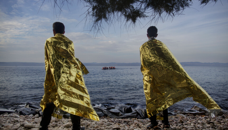 To syriske flyktninger står på stranden på Lesbos og ser ut på Middelhavet hvor nye flyktninger er på vei mot håpet. Foto: Espen Ramussen/VG.