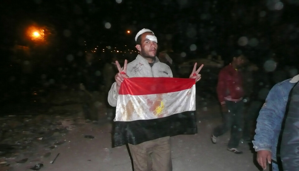 Tahrir-plassen. Natt til 3. februar. Regimekritiker viser seierstegn og et blodig flagg etter å ha slåss mot Mubarak-tilhengere. Foto: aljazeeraenglish (Flick.com)