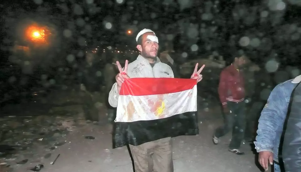 Tahrir Square. Natt til 3. februar. Regimekritiker viser seierstegn og et blodig flagg etter å ha slåss mot Mubarak-tilhengere. Foto: aljazeeraenglish (Flick.com)