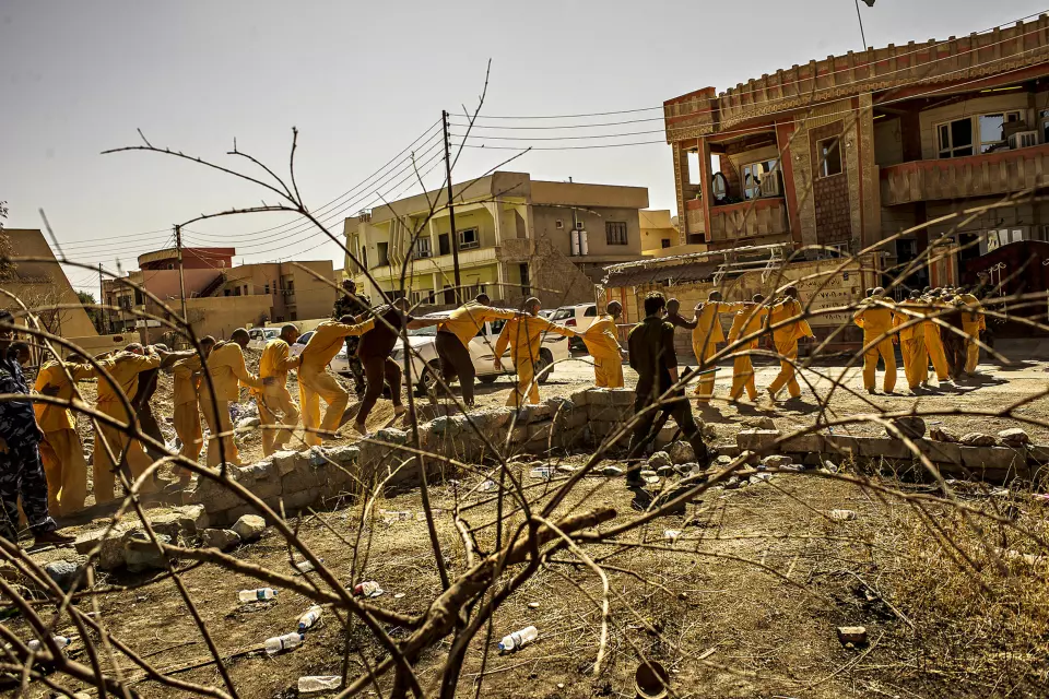 En gruppe mistenkte IS-medlemmer føres fra fangetransporten til rettsbygningen i den kristne byen Qaraqosh – byen som IS noen måneder tidligere la i ruiner. De skyldige risikerer å møte galgen i Bagdad. Foto: André Liohn