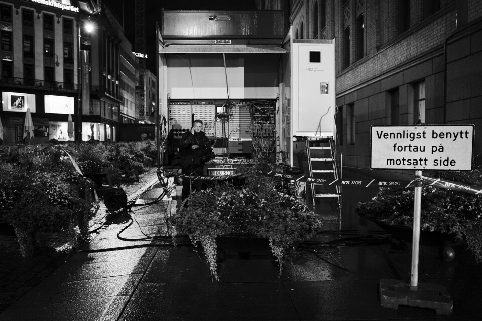 Utenfor Stortinget på Karl Johan står en ensom kameramann fra NRK i ly for regnet ved traileren.