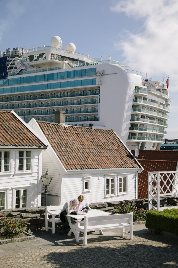 To turister kikker på et kart i gamle Stavanger. Bak idyllen ruver skip med tusenvis av passasjerer. To turister kikker på et kart i gamle Stavanger. Bak idyllen ruver skip med tusenvis av passasjerer.