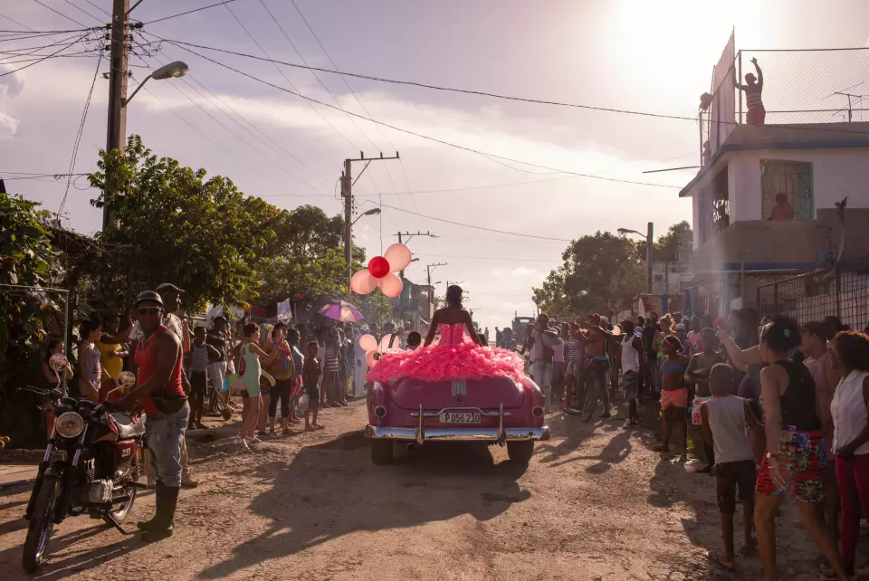 Pura kjører rundt i nabolaget i en rosa bil fra 50-tallet, mens lokalsamfunnet samler seg for å feire hennes 15-årsdag i Havana, Cuba. Foto: Diana Markosian / Magnum Photos