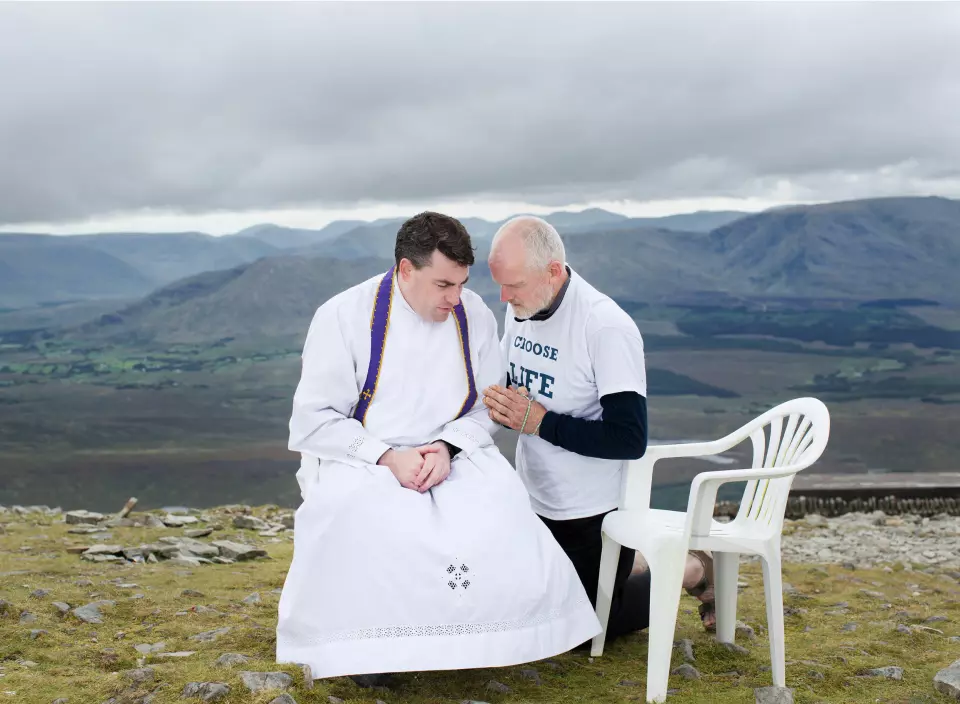 Aidan ber med en prest etter skriftemål, på toppen av det hellige fjellet Croagh Patrick, i County Mayo i Irland. Mange pilegrimer kommer til dette fjellet, inkludert en pro-livsgruppe for menn. Foto: Olivia Harris