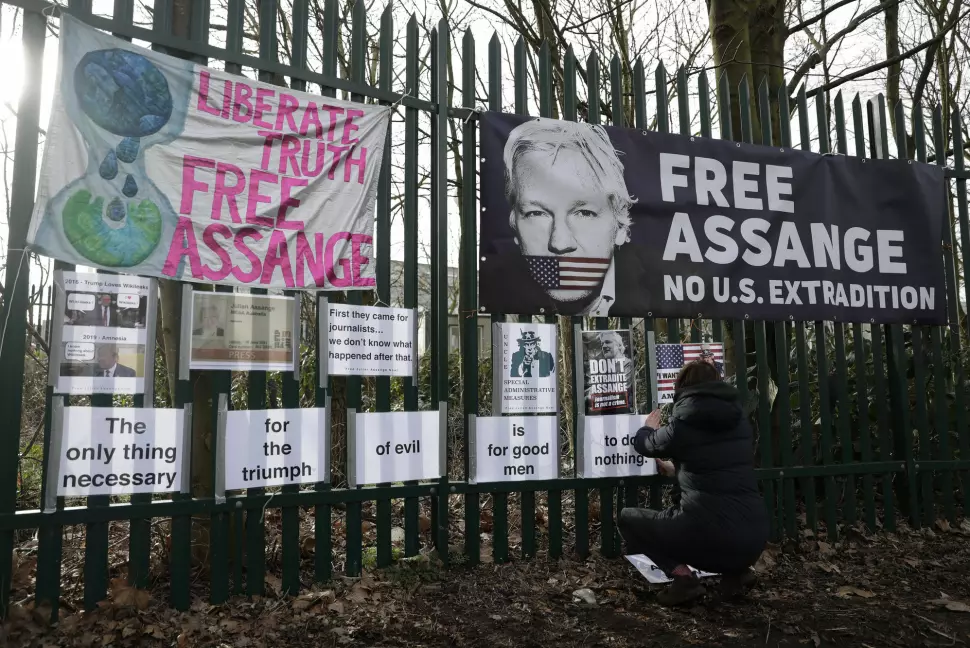 En av Julian Assanges støttespillere henger opp protestplakater mot at WikiLeaks-grunnleggeren utleveres til USA.