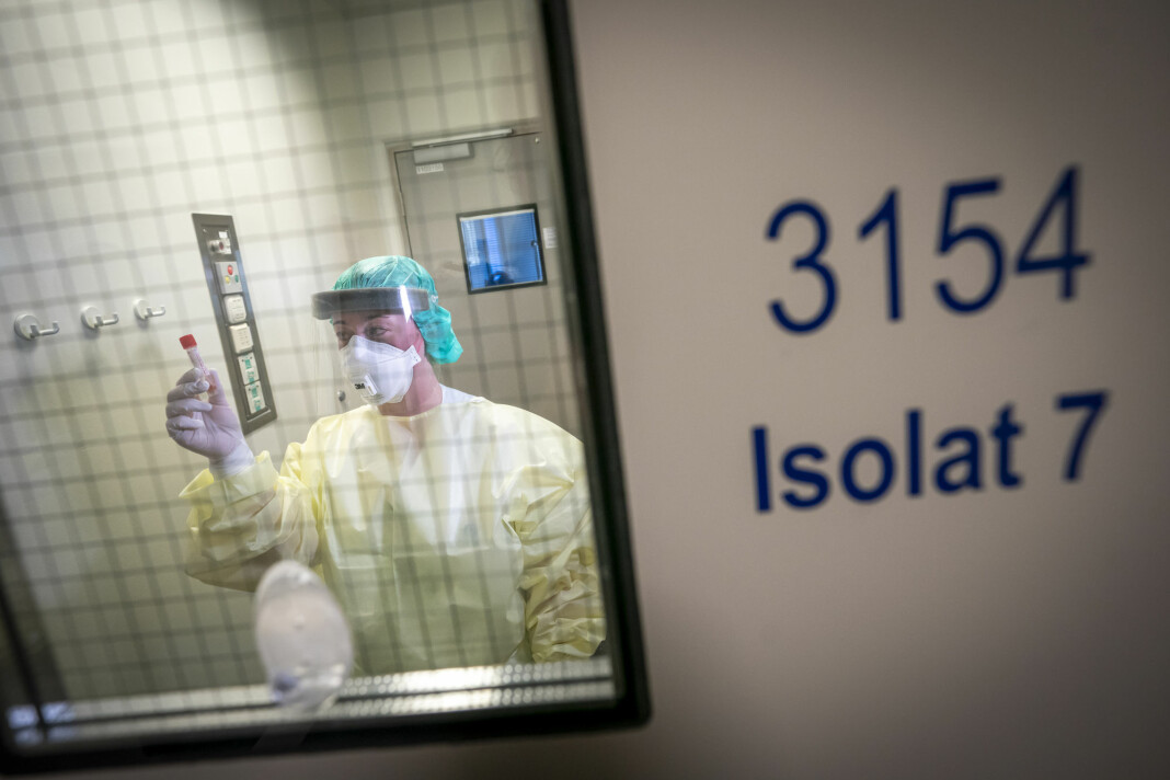Fagutviklingssykepleier Marte Rygh Selmer ikledd smittevernutstyr ser på en spyttprøve på isolatposten på Ullevål sykehus.