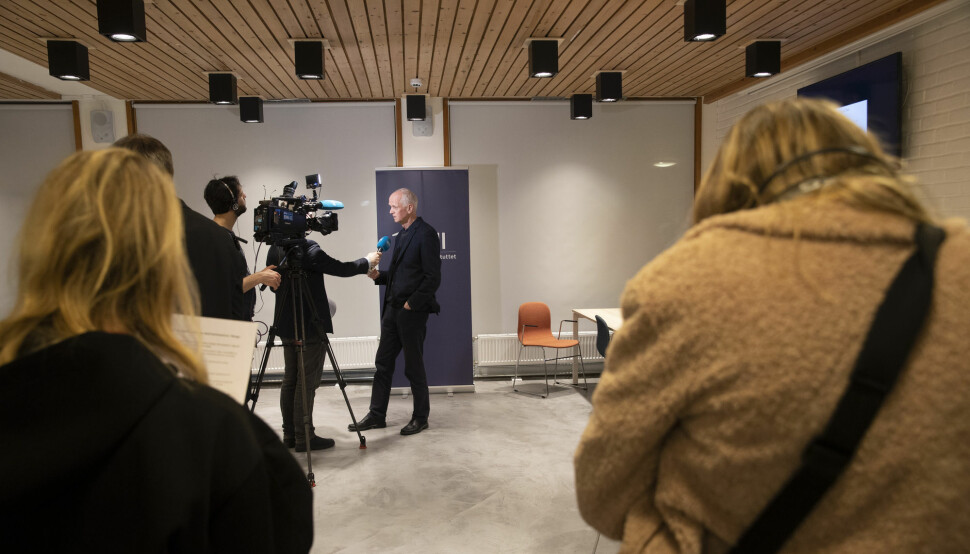 Områdedirektør Geir Bukholm i Folkehelseinstituttet blir intervjuet, mens andre står i kø.