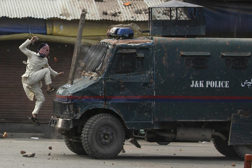 En maskert mann hopper mot et kjøretøy tilknyttet indisk politi i Kashmir i mai 2019. Bildet er tatt av fotografen Dar Yasin, som vant Pulitzer som bildene tatt fra området.