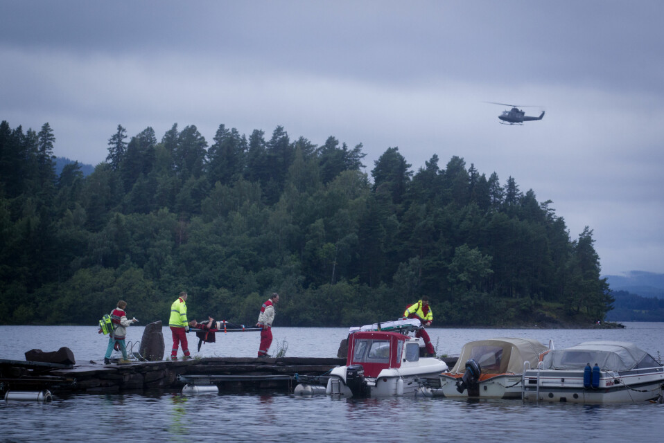 En AUF-ungdom blir fraktet bort på fastlandssiden ved Utøya. I bakgrunnen ser vi Utøya og helikopter fra forsvaret.