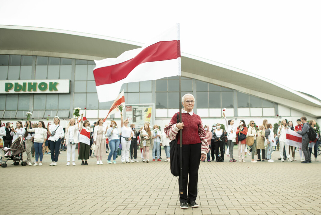 En kvinne holder opp det historiske flagget til Hviterussland under en demonstrasjon mot president Aleksandr Lukasjenko i Minsk lørdag.