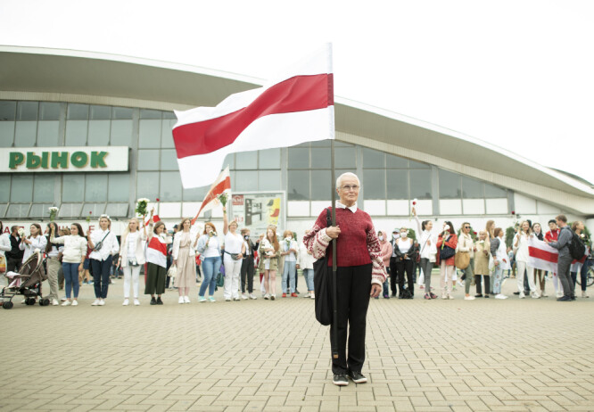 En kvinne holder opp det historiske flagget til Hviterussland under en demonstrasjon mot president Aleksandr Lukasjenko i Minsk lørdag.