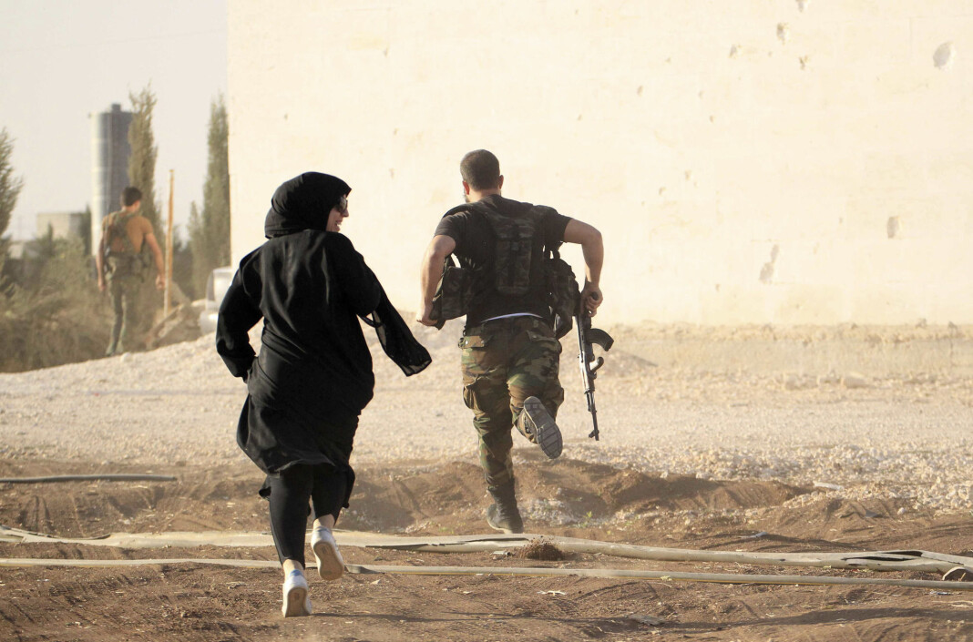 Kvinnelige reporter løper sammen med soldat for å unngå snikskyttere utenfor Aleppo i Syria i 2014. Kvinnelige reporter løper sammen med soldat for å unngå snikskyttere utenfor Aleppo i Syria i 2014.