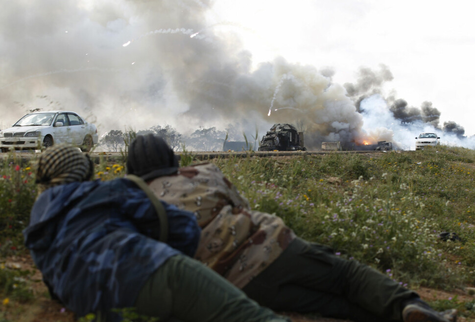 Opprørssoldater ligger i dekning og ser på at regjeringsstyrkene blir angrepet av fly. Bildet er fra 2011.