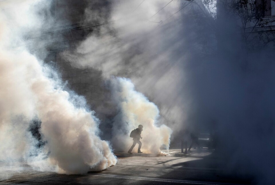 En fotograf løper vekk fra tåregassen under en koronademonstrasjon i Hellas tidligere i år.