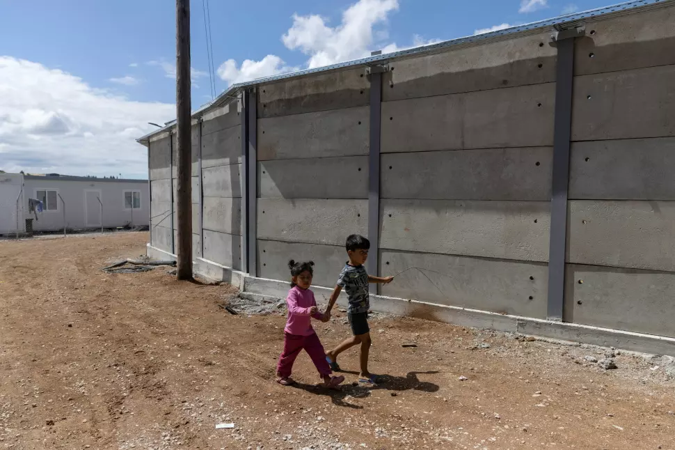 Barn går ved de nye betongmurene inne i flyktningleiren Ritsona i Hellas i juni 2021.