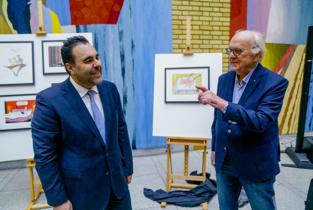 Stortingspresident Masud Gharahkhani sammen med Inge Grødum, som tegnet Putin ved det karakteristiske lange bordet sitt. Stortingspresident Masud Gharahkhani sammen med Inge Grødum, som tegnet Putin ved det karakteristiske lange bordet sitt.