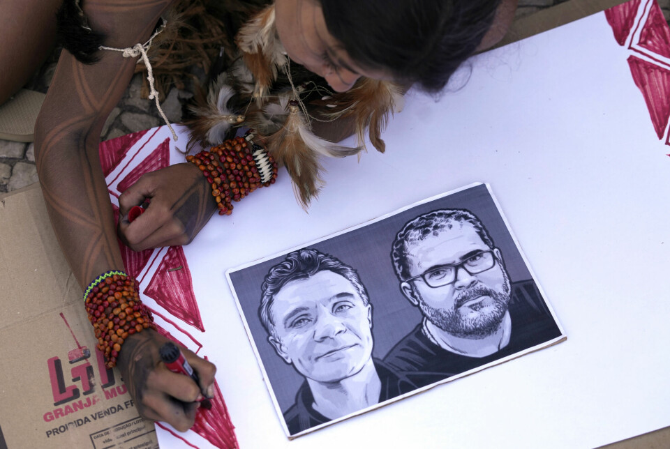 En jente fra den brasilianske urbefolkningen farger en plakat med et bilde av den drepte britiske journalisten Dom Phillips og urfolkseksperten Bruno Pereira.