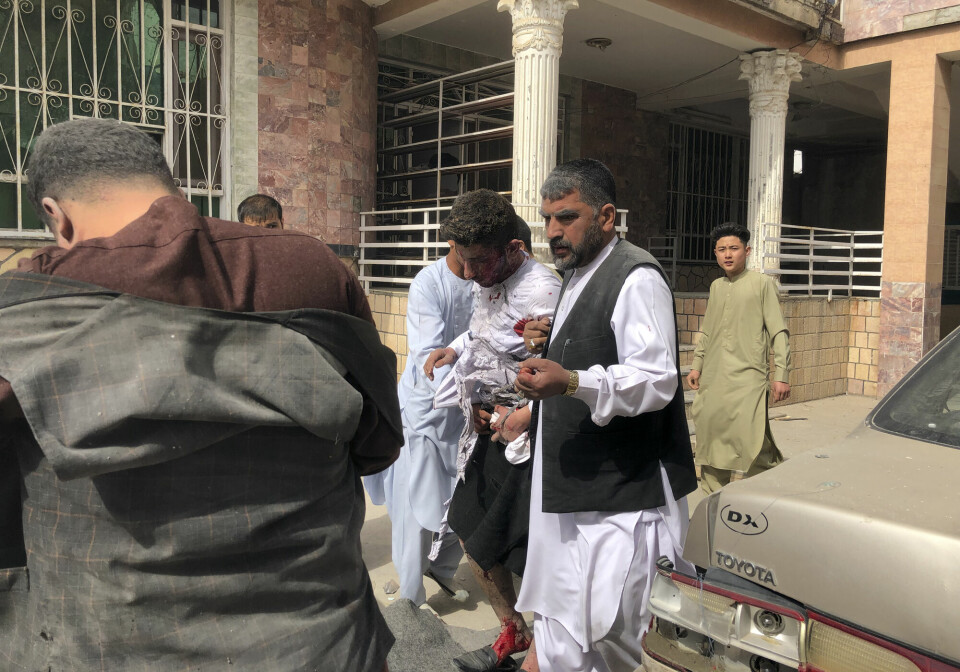 En såret mann blir hjulpet ut etter bombeeksplosjonen i Mazar-e-Sharif.