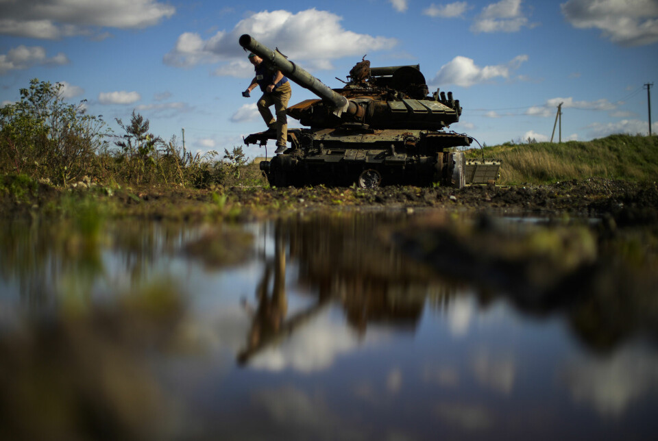 En journalist tar et bilde fra en ødelagt russisk tank i Ukraina.